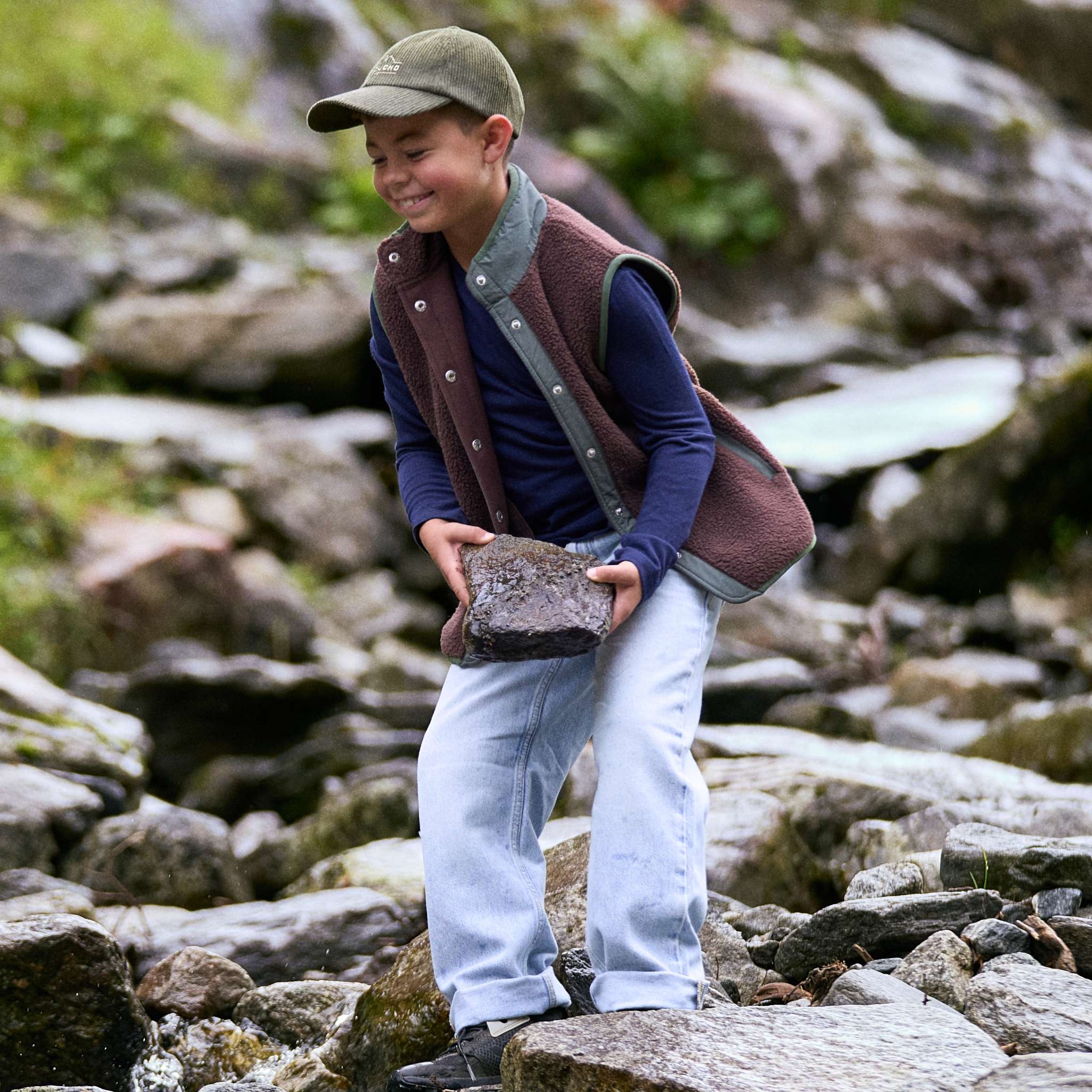 Boy playing with a rock by a river