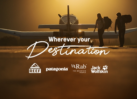 Man and a woman walking away from a private jet, carrying a backpack and The North Face duffle bag in a dusk.