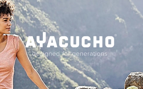 Man and woman walking away from old cars wearing Ayacucho gear.