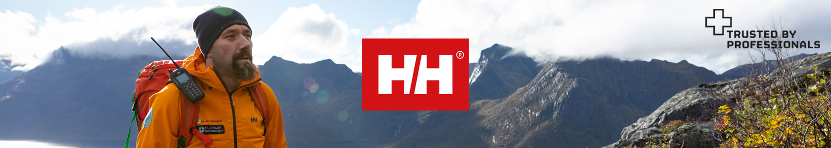 A man wearing a orange Helly Hansen jacket, a scenery of mountains touching the clouds and the Helly Hansen logo in the centre
