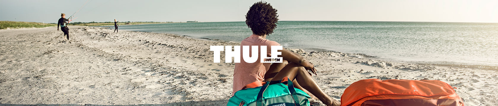 People on a beach with a Thule duffel.
