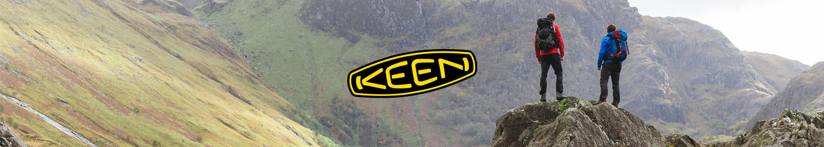 Two people are standing on a rock in Keen boots