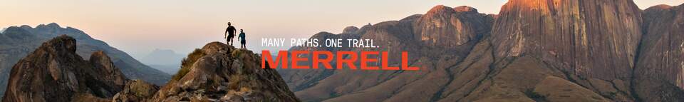 Female and male legs in Merrell footwear in the middle of a sandy road.