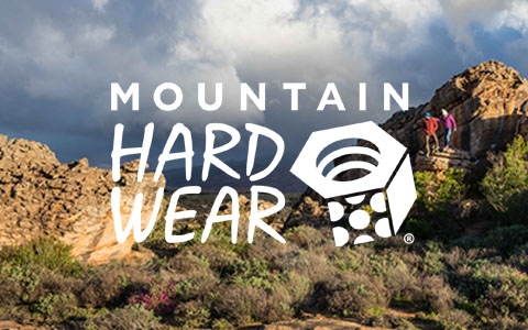 Two people standing on a big rock, wearing Mountain Hardwear clothing