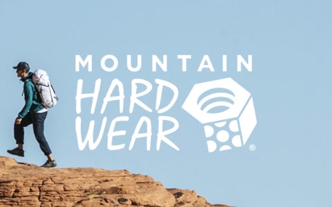 Two people standing on a big rock, wearing Mountain Hardwear clothing