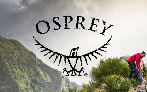 A couple with Osprey backpacks walking up a rocky hill somewhere in the mountains.