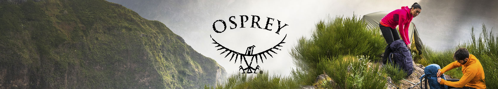 A couple with Osprey backpacks walking up a rocky hill somewhere in the mountains.