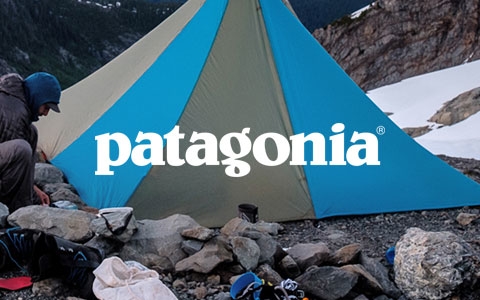 Two people setting up camp on a rocky mountain, wearing Patagonia gear.