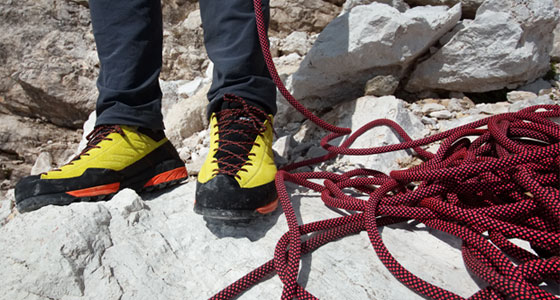 An image of a person's shoes next to some climbing rope 
