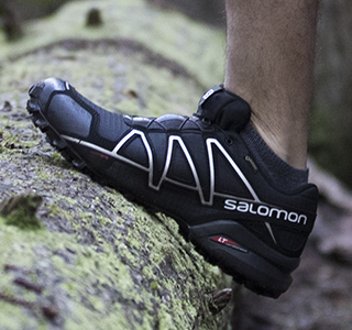 Man leaning on a tree wearing Salomon footwear