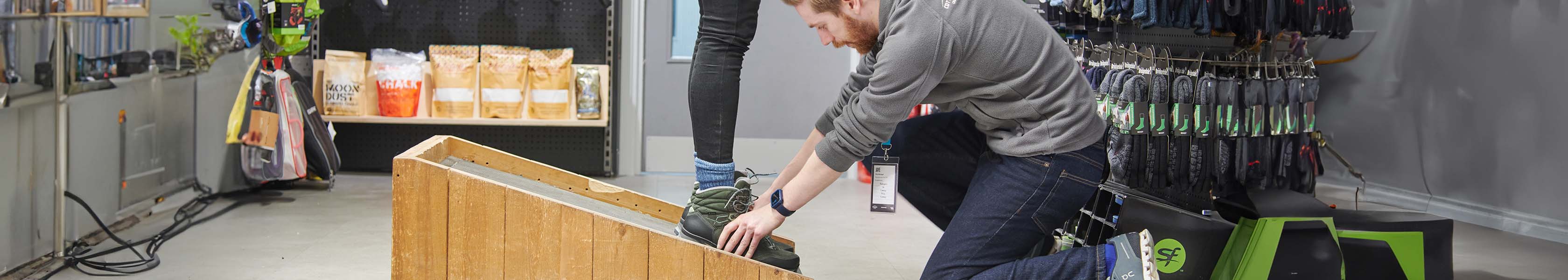 An image of an in-store expert, fitting a customer for walking boots 