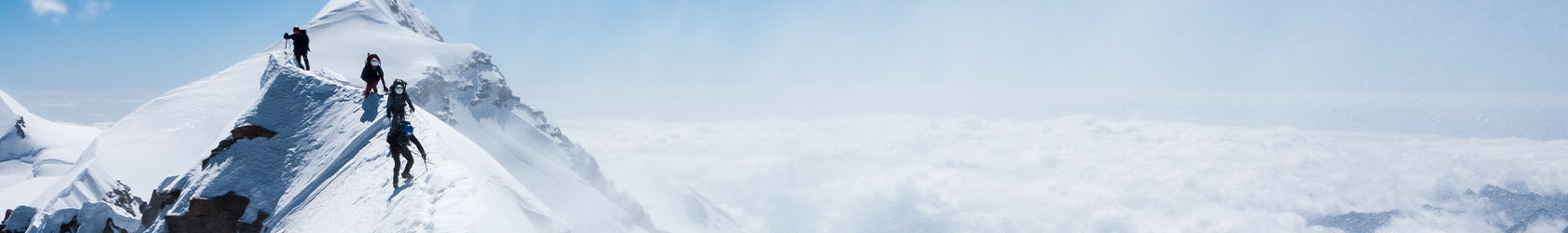 A man in snow mountains, wearing mountaineering gear.