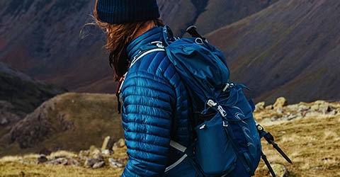A person is walking on mountains, wearing a rucksack