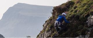 Man Climbing Grassy Rock Face