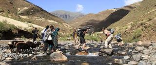 People crossing a river in a valley