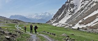 Three hikers walking through a mountainous valley