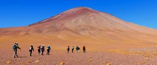 Group of hikers walking towards volcano