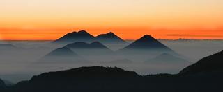 Volcanoes at sunrise or sunset surrounded in mist