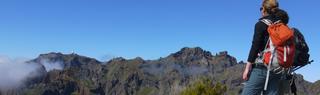 Woman with backpack looking over a mountain range