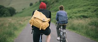 Two people on bikes with Millican Backpacks