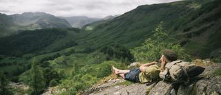 Man lies on rock against Millican backpack