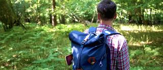 Man walks through the woods with his Millican rucksack