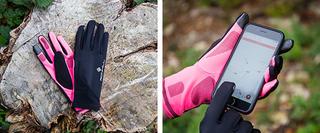 A pair of gloves on a tree stump, and a person using an iphone whilst wearing the gloves