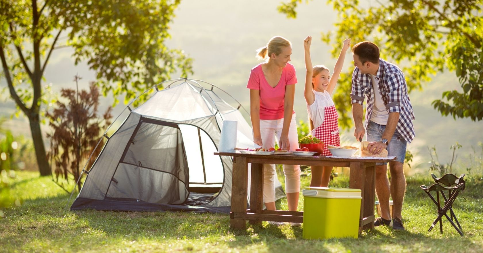 A couple cooking with their child at their campsite