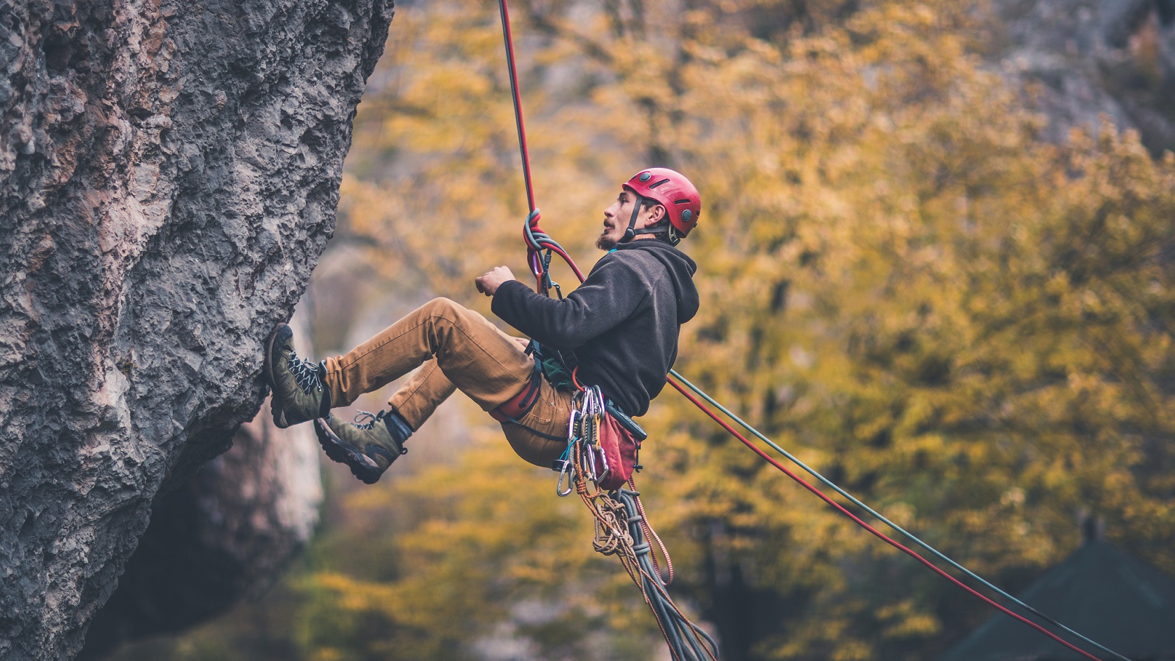 A man climbing up a rock face on a rope