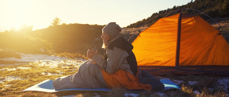 A person on a camping trip sat on a sleeping mat 