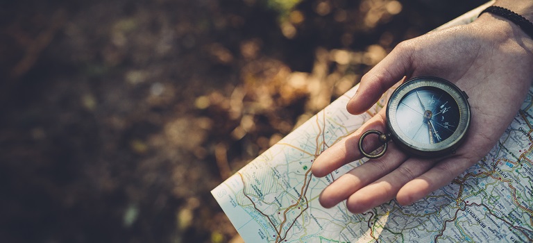 Teenager girl with Compass Reading a Map in the forest.
