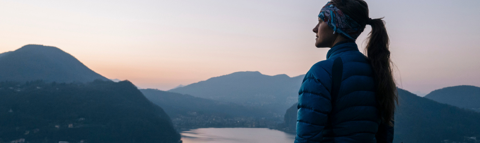A woman wearing an insulated midlayer looking out at the mountains 