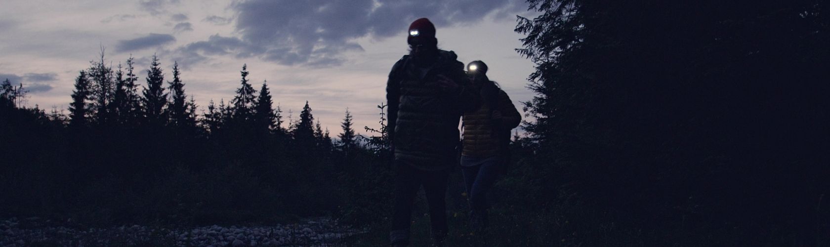 Two people walking at night wearing head torches 