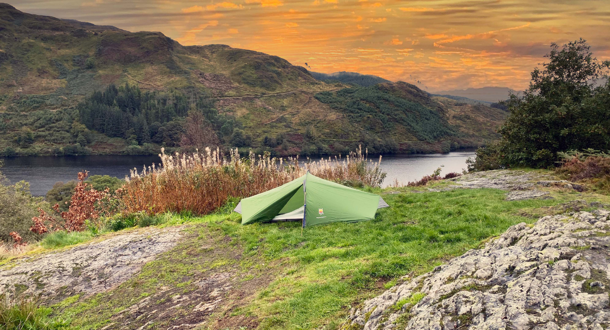 Red tent pitched near woodland