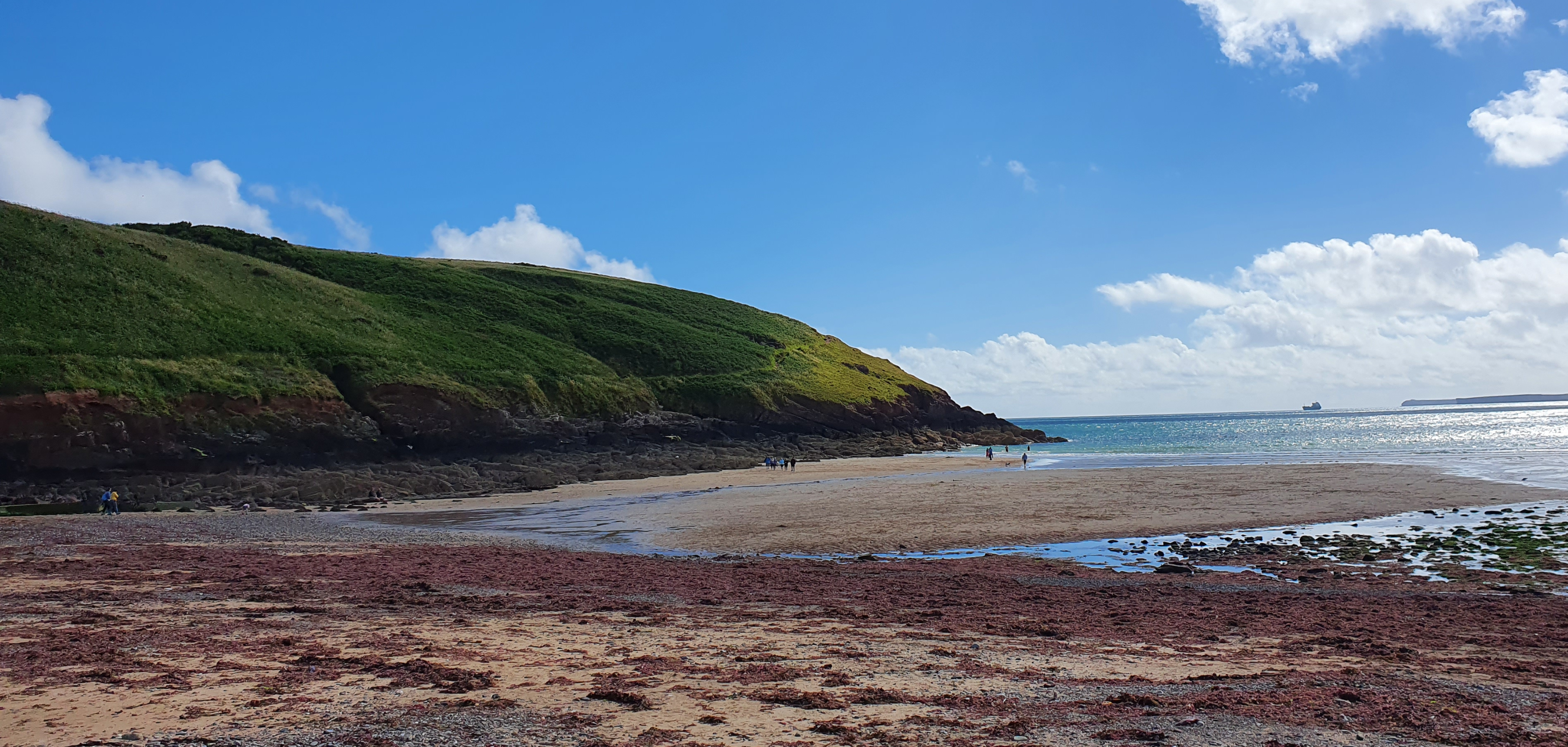 A beach and ocean with a large hill in rthe background