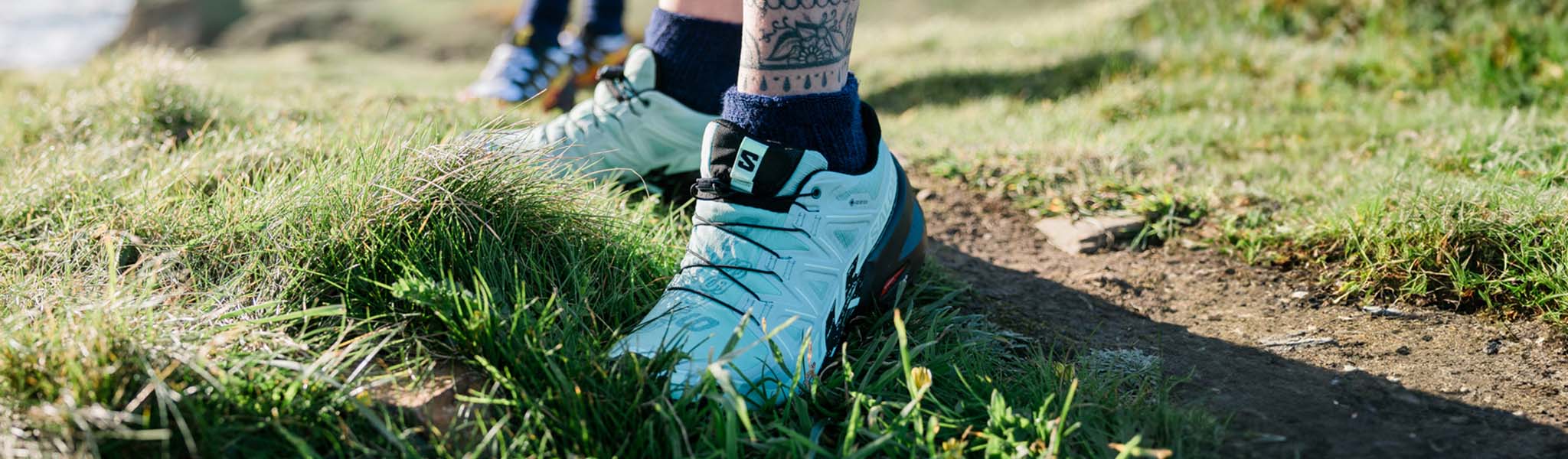 Person's feet in light blue Salomon shoes on the grass