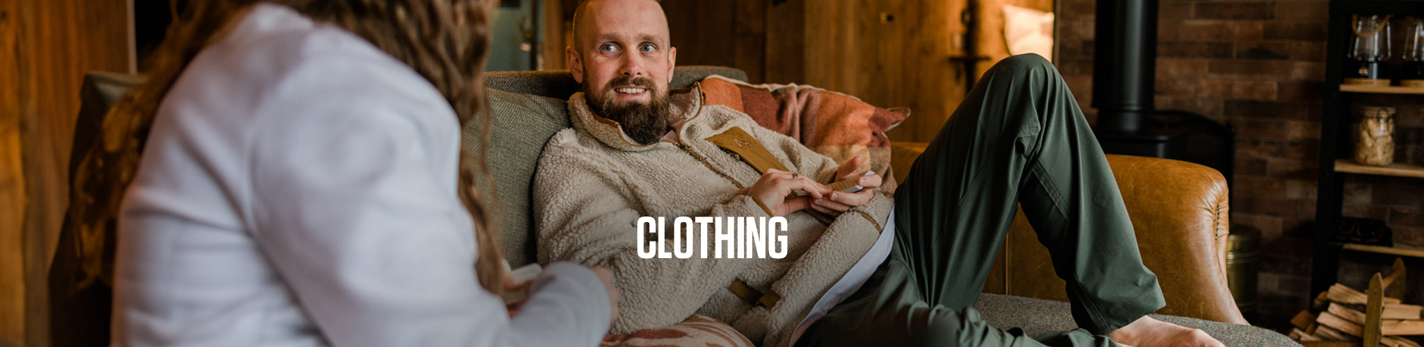 A man is sitting on a sofa, wearing walking kit, including fleece.