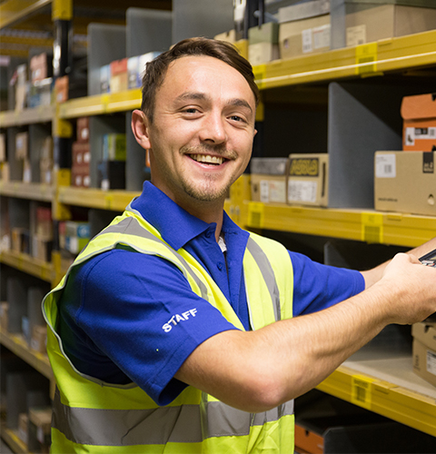 Man scanning a box at a warehouse and smiling at the camera
