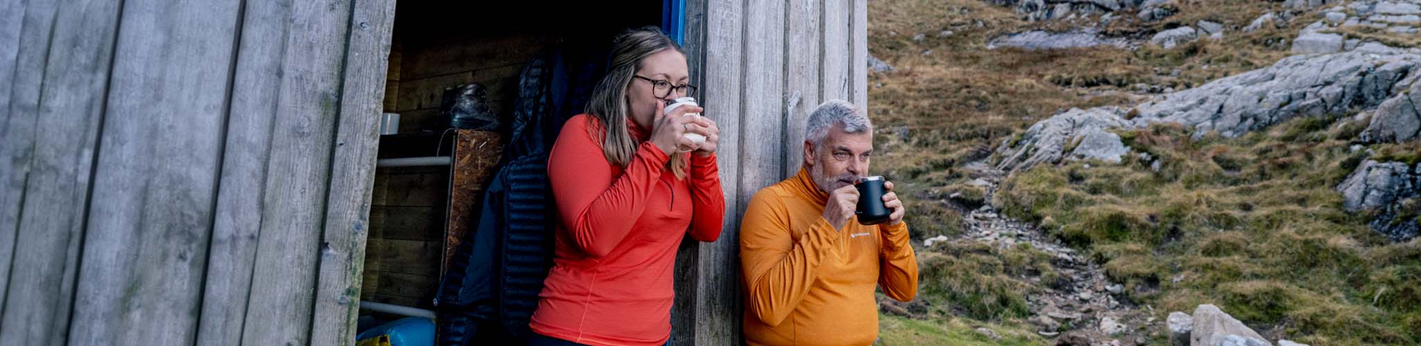 Shop midlayers. A man and woman drinking coffee at a hut in their fleeces