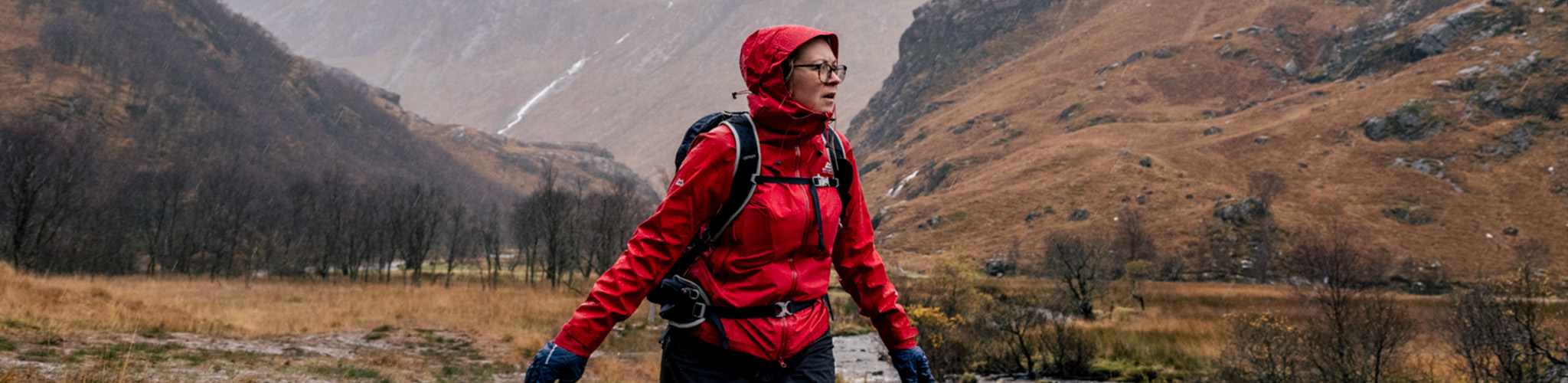 Shop Waterproof jackets. A person hiking in a red waterproof jacket 