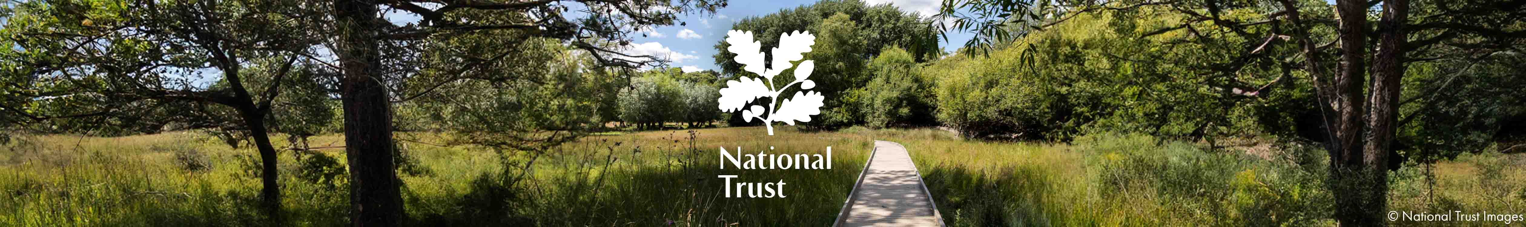 A couple with two children are walking next to one of the National Trust houses. 