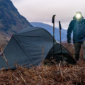 Man with head torch setting up a tent