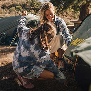 camping - two people putting up a tent