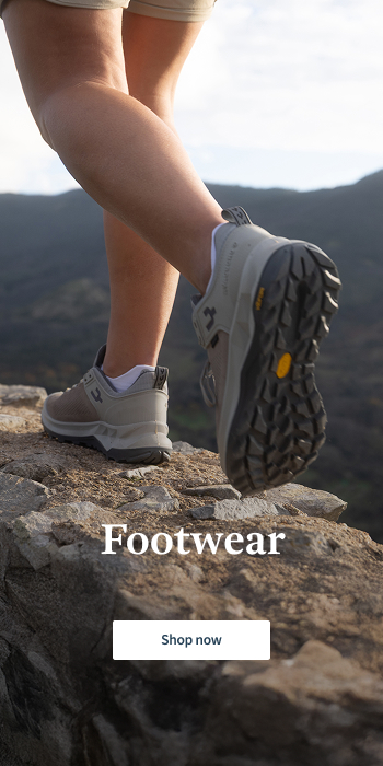 Two Women walking ontop of small wall in the nature wearing walking shoes and shorts