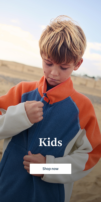 Boy wearing a blue and orange fleece near the beach