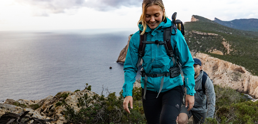 Woman and man walking in the costatal path with views to a clif and sea