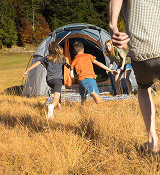 Two people next to a tent on a mountain.