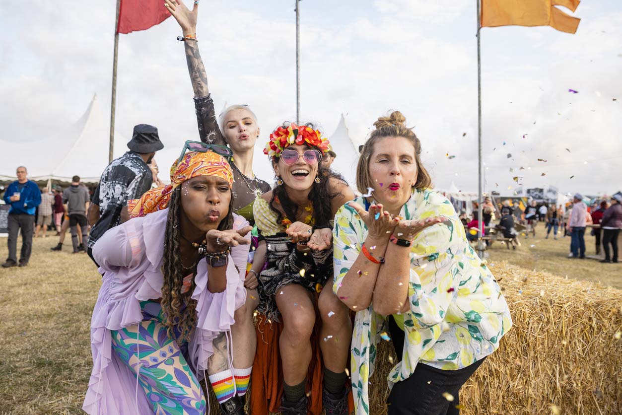 Three ladies smiling at the camera in festival clothing