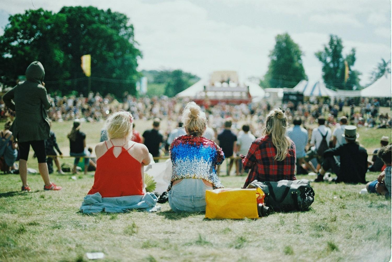 Three people sat in a field at Wilderness Festival