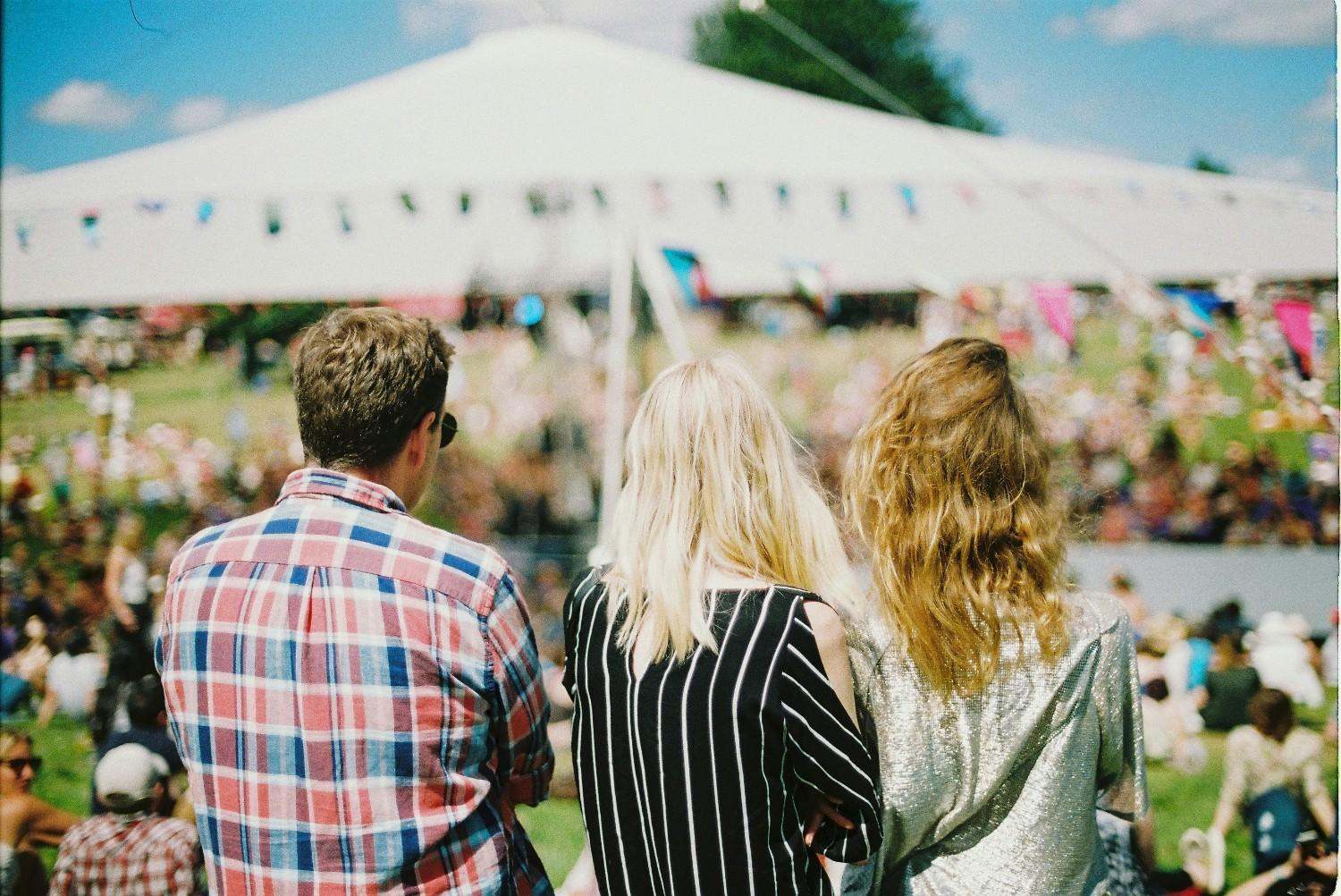 People in the sunshine by a tent at Wilderness Festival